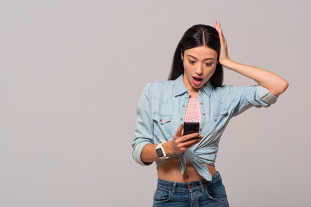 How can it be. Pleasant emotional surprised woman holding cell phone and expressing wonder while...