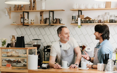 Friendly air. Portrait of two happy and cheerful waiters drinking coffee while the break at coffee shopの写真素材