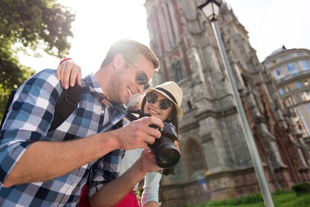 Happy together. Cheerful delighted couple smiling and using photo camera while embracingの写真素材