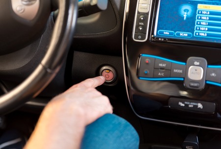 Just press the button. Close up of a finger of a man pressing the run button in the car