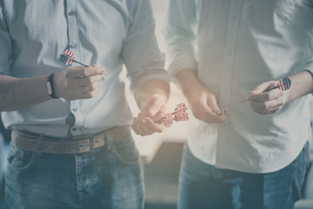 Cooperating power. Inspirational typographic message for international relationships with cropped image of two men holding darts with a flag of USA in a backgroundの写真素材