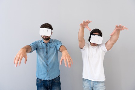 Zombies. Young involved men holding hands in front of them and using virtual reality deviceの写真素材