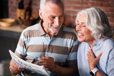 Funny. Attractive old couple having fun while reading morning newspaper