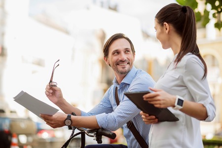 Happy to be your colleague. Young ambitious colleagues with documents and tablet enjoying each others company while going to lovely workの写真素材