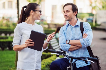 You will not believe. Happy ambitious woman telling her young male colleague on a bicycle surprising news.の写真素材