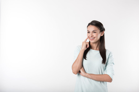 True emotions. Cheerful content smiling woman holding her hand on the chin and smiling while standing against white backgroundの写真素材