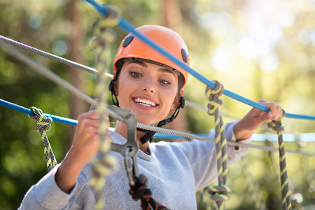 Safety is above everything. Nice positive careful woman holding a mountain carabiner and looking at it while checking the safety equipmentの写真素材