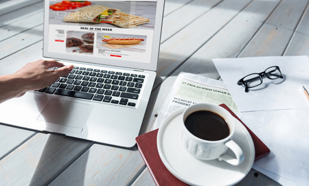 Time for hobby. Close up portrait of woman using her new laptop on floor near freshly-made coffee cup, book and newspaper.の写真素材