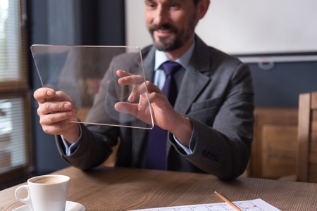 Technological device. Selective focus of a modern innovative tablet being is hands of a happy hard working handsome businessmanの写真素材