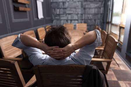 I deserve to rest. Happy calm relaxed man resting his head on the hands and relining in the chair while enjoying his relaxationの写真素材