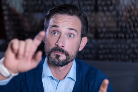 Technological innovations. Handsome curious bearded man sitting and looking at the virtual panel...