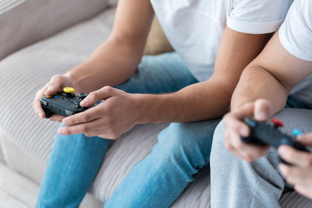 Delightful relaxation. Joyful relaxed happy gay couple smiling and playing console games together...