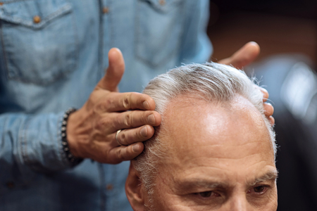 Looking good. Close up of male hairstylist touching senior clients temples while using special hair gel.の写真素材
