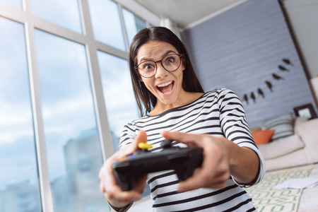 Winner of the game. Joyful delighted excited woman sitting at home and holding the game console...