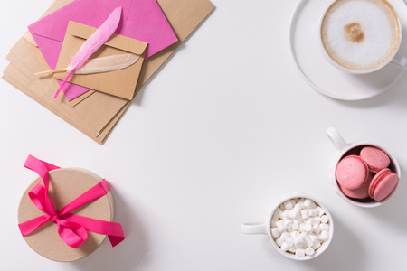 Confession of love. Pink feathers lying on the pile of paper envelopes near the gift box tied with pink ribbonの写真素材