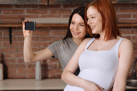 Say cheese. Happy friends wearing home clothes spending weekends with pleasure while making photo on...
