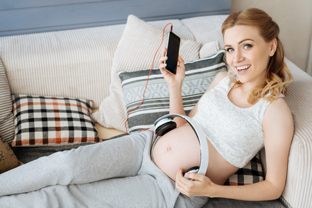 Pregnant woman listening to music on headphonesの写真素材
