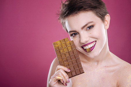 Cheerful woman holding chocolate bar