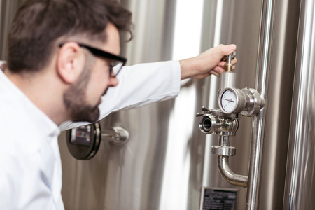 Happy man using mechanism on brewing factoryの写真素材