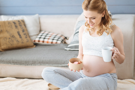 Pregnant woman drinking tea with macaroonsの写真素材