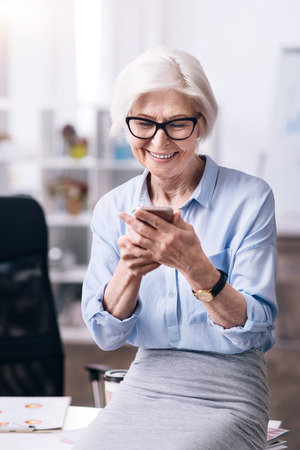 Involved smiling woman using the smartphone in the officeの写真素材