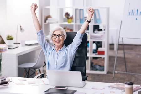 Amused aged businesswoman expressing joy in the officeの写真素材