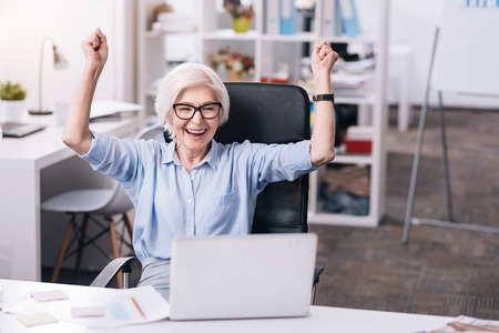 Glad aged businesswoman expressing positivity at workの写真素材
