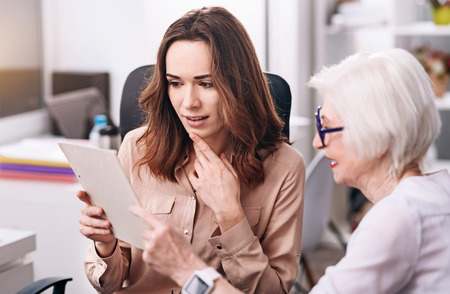 Attentive businesswomen sharing ideas in the officeの写真素材