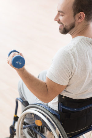 Smiling young disabled man training with weights in the gymの写真素材