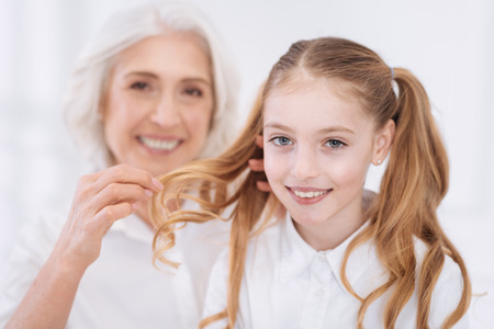 Loving positive senior woman taking care of her little granddaughter