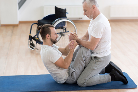 Proficient general practitioner assisting the handicapped in the gymの写真素材