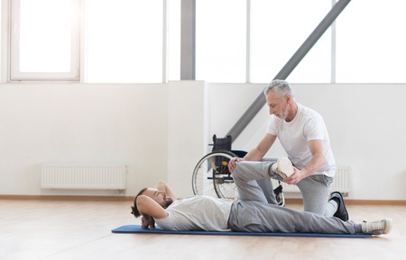 Proficient aged orthopedist working out with handicappedの写真素材