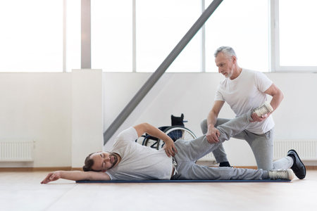 Involved physical therapist stretching the handicapped in the gymの写真素材