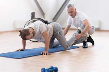 Aged physical therapist stretching the handicapped in the gymの写真素材