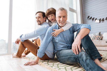 Handsome cheerful men sitting on the floorの写真素材