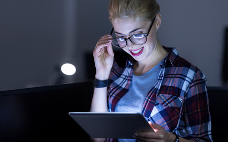 Charismatic IT girl testing gadgets in the dark lighted roomの写真素材