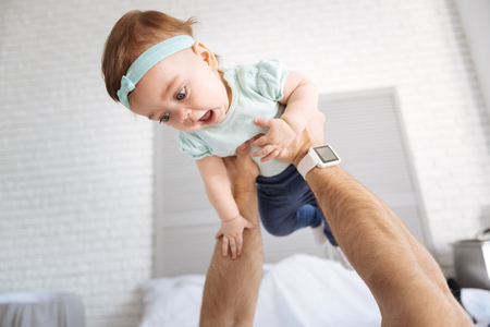 Delighted little girl relaxing with her father at homeの写真素材