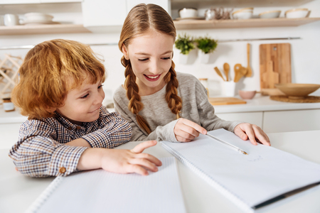 Diligent girl helping her little brotherの写真素材