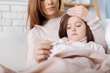 Caring mother measuring temperature of her ill daughterの写真素材