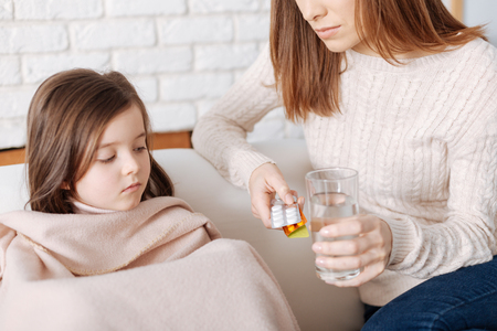 Pleasant loving mother giving pills to her sick daughterの写真素材