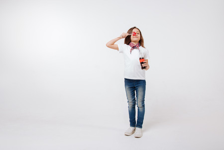 Funny little girl holding bottle and lollipop in the studioの写真素材