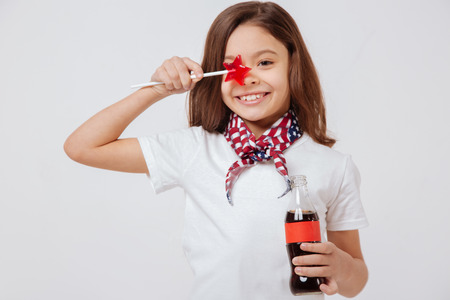 Happy little girl holding bottle and lollipop in the studioの写真素材