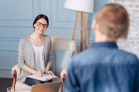 Positive delighted woman psychologist looking at her little patientの写真素材