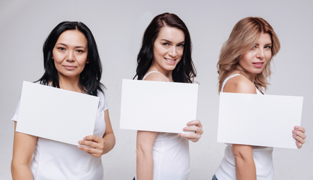Beautiful women of different ethnicities demonstrating white signsの写真素材