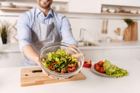 Talented bachelor cooking vegetable salad at homeの写真素材
