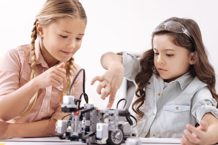 Funny little girls exploring technologies at schoolの写真素材