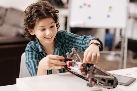 Amused teen boy programming digital robot in the studioの写真素材