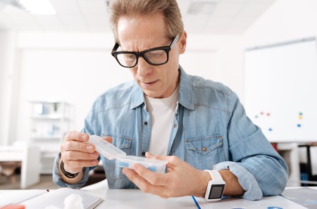 Confident elderly man holding box with pills