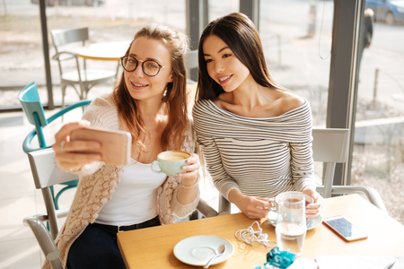 Two girlfriends making selfies in the cafeの写真素材