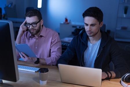 Nice male programmer consulting the bookの写真素材